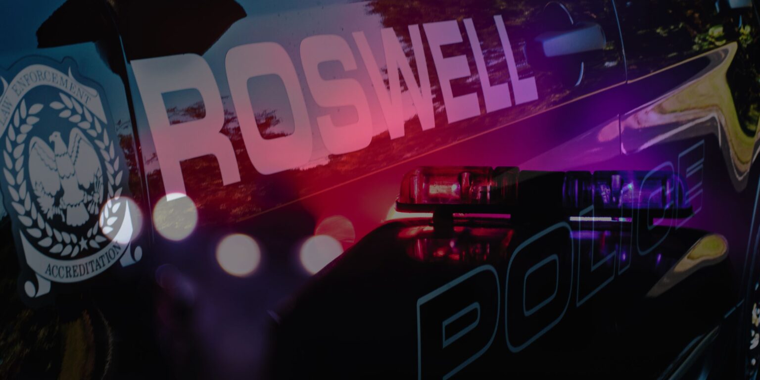 A photo showing the side of a Roswell Police Car with the reflection of blue and red lights on it.