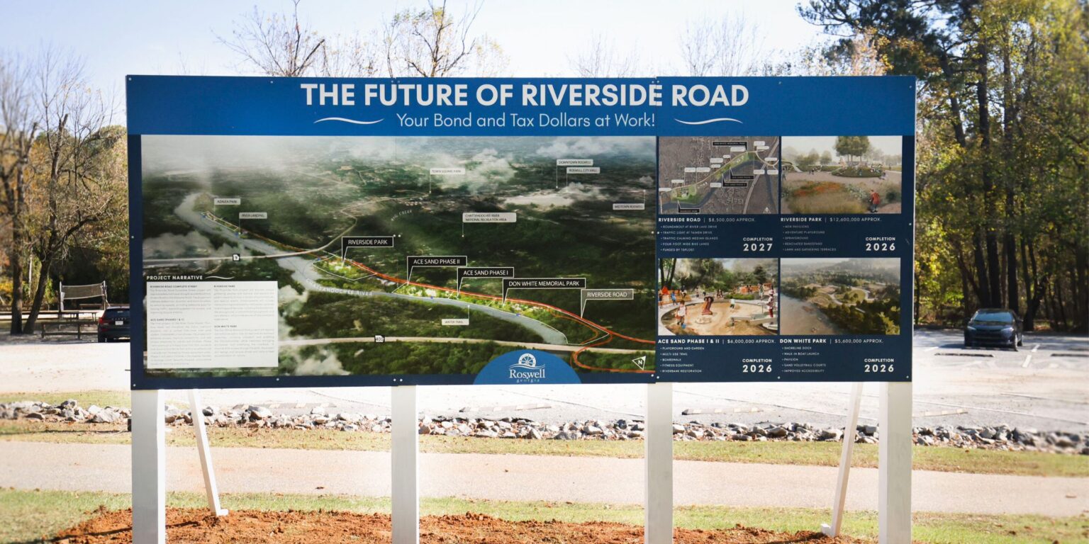 A sign on the side of Riverside Road depicts City projects along the road.