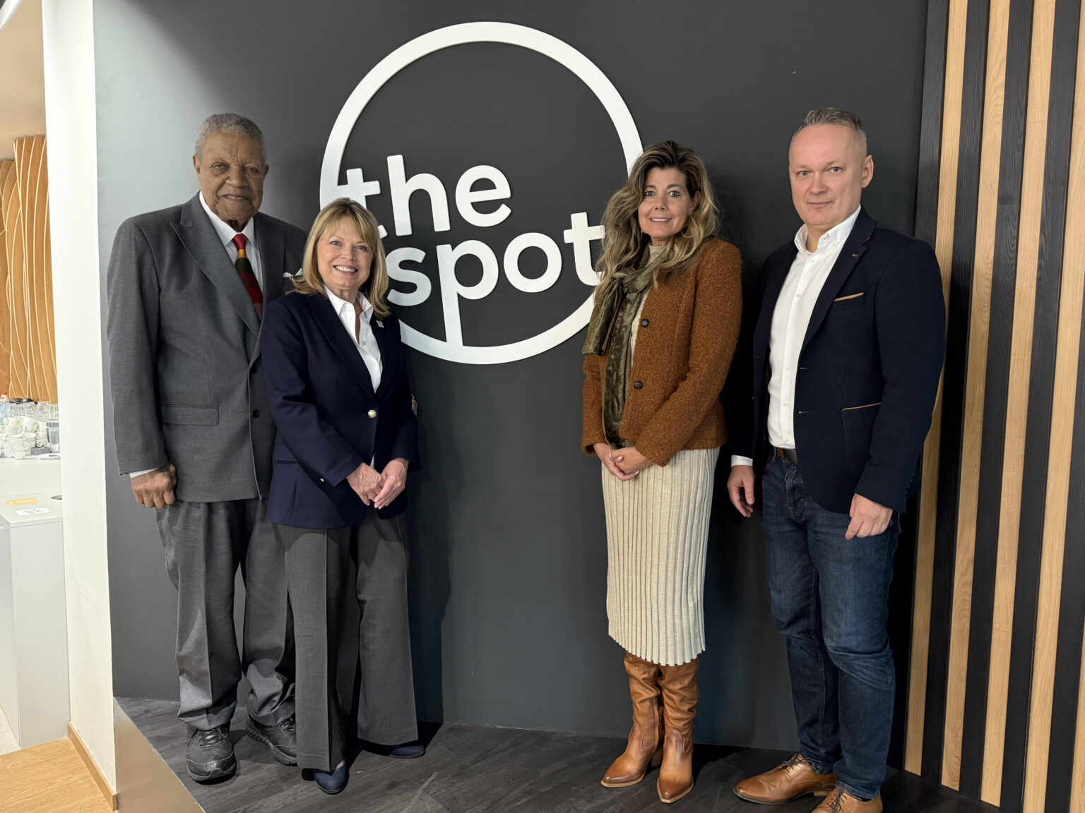 City and state officials pose in front of a sign that say, "The Spot."