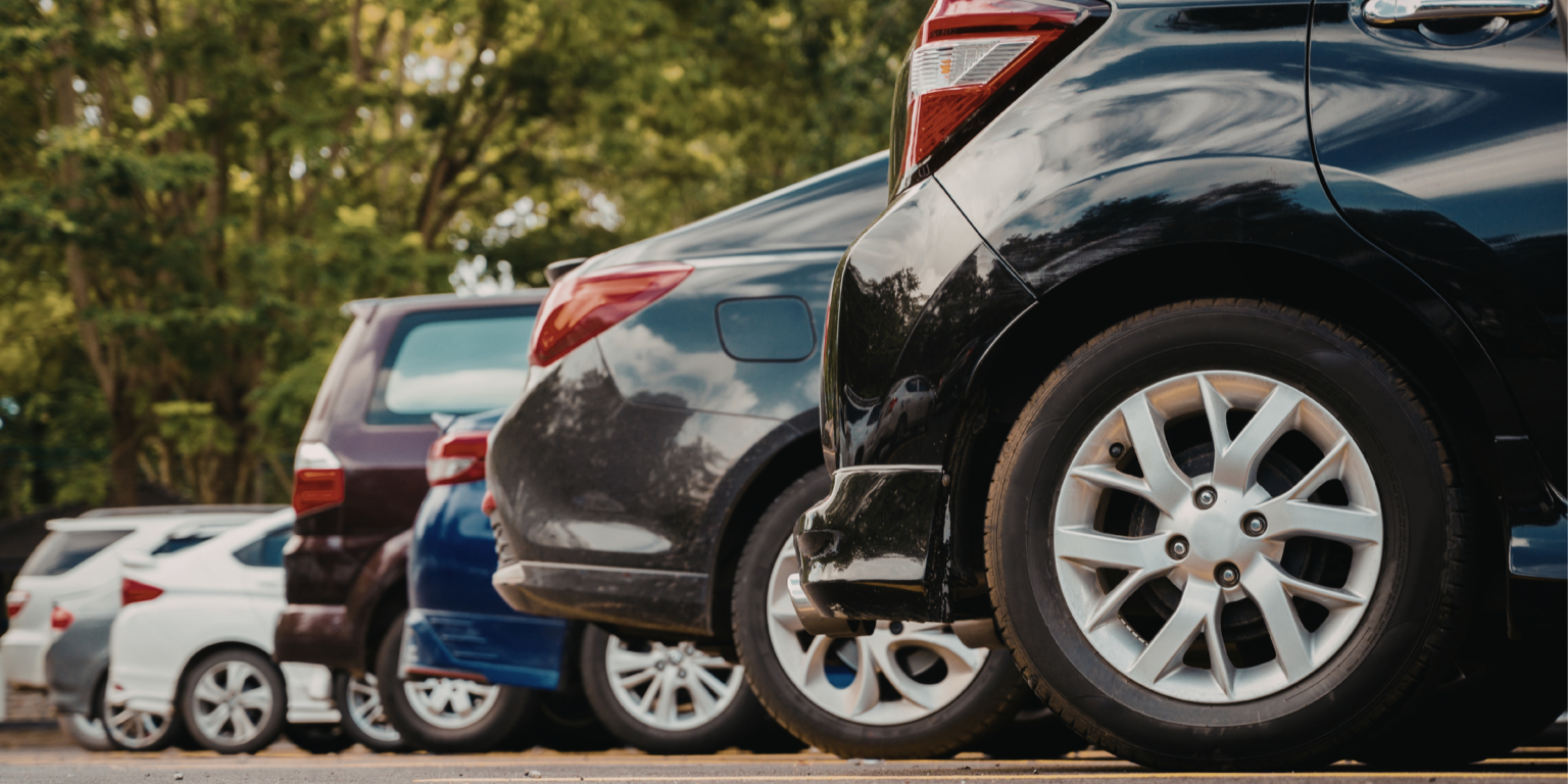 A photo of a line of cars parked in a lot.